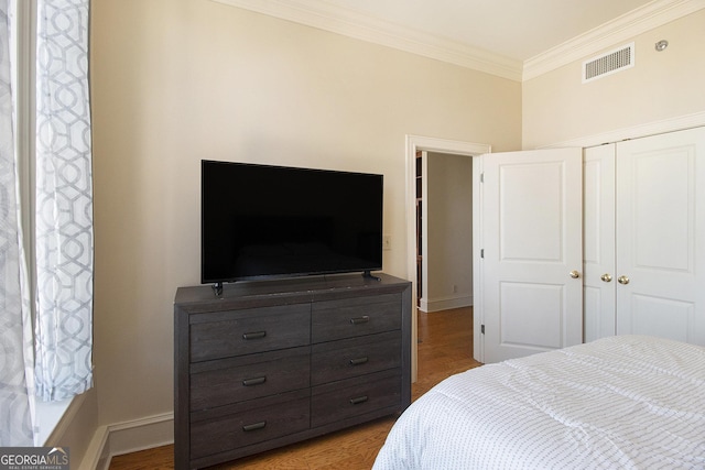 bedroom with visible vents, ornamental molding, baseboards, and wood finished floors