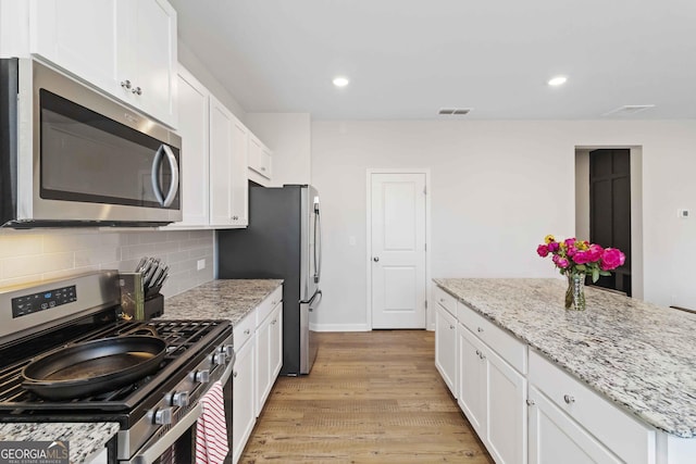 kitchen with decorative backsplash, white cabinets, and stainless steel appliances