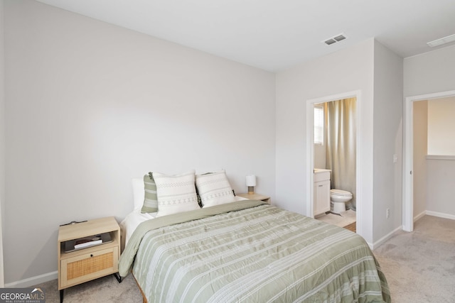 bedroom with visible vents, baseboards, light colored carpet, and ensuite bathroom