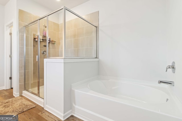 full bathroom featuring wood finished floors, a stall shower, and a bath