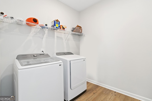 washroom featuring baseboards, light wood-style floors, laundry area, and washer and clothes dryer