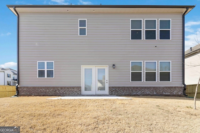 rear view of property with brick siding, a yard, and fence