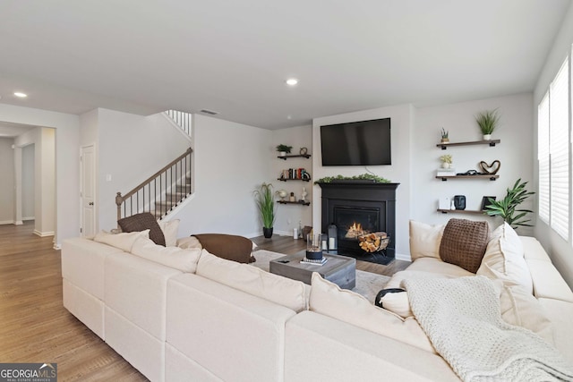 living area featuring recessed lighting, stairway, a fireplace with flush hearth, and light wood-style flooring