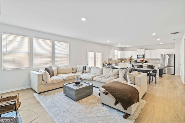 living room featuring recessed lighting, baseboards, and light wood-style floors