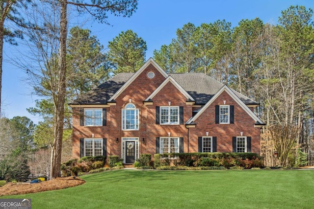 colonial house with a front lawn and brick siding