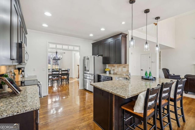 kitchen with a peninsula, wood finished floors, light stone countertops, and appliances with stainless steel finishes