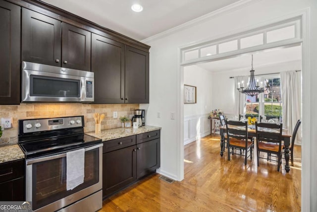 kitchen with dark brown cabinets, decorative backsplash, appliances with stainless steel finishes, and crown molding