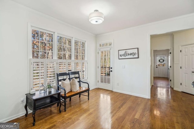 sitting room featuring wood finished floors, baseboards, and ornamental molding