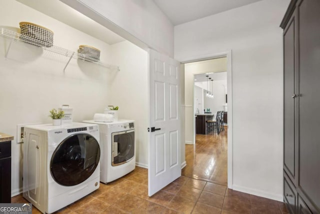 clothes washing area featuring dark tile patterned floors, laundry area, washer and dryer, and baseboards