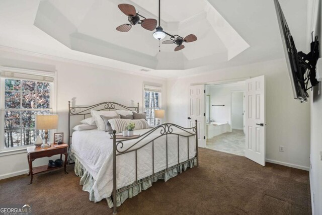 carpeted bedroom featuring ensuite bathroom, a ceiling fan, a raised ceiling, and baseboards