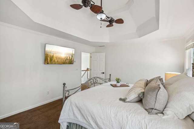 carpeted bedroom featuring baseboards, a raised ceiling, a ceiling fan, and crown molding