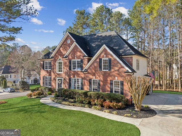 view of front of property featuring brick siding, driveway, and a front lawn