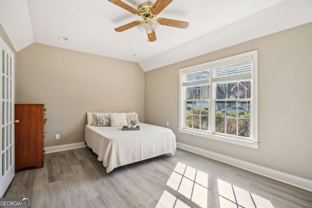 bedroom with baseboards, lofted ceiling, wood finished floors, and a ceiling fan