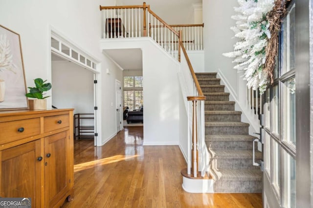 entrance foyer featuring stairway, baseboards, a high ceiling, and wood finished floors