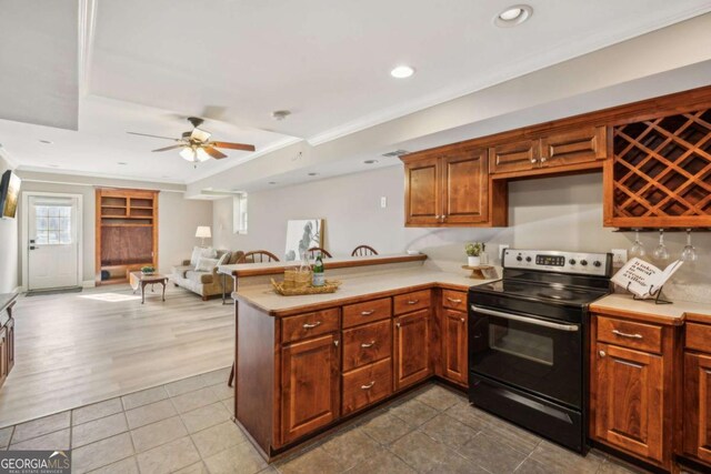 kitchen featuring a peninsula, light countertops, and range with electric stovetop