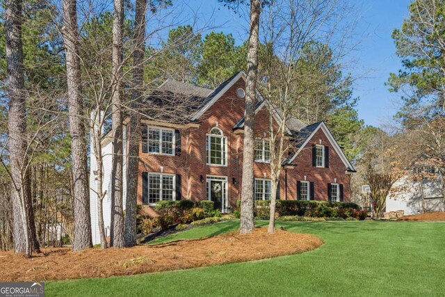 colonial home with a front yard and brick siding