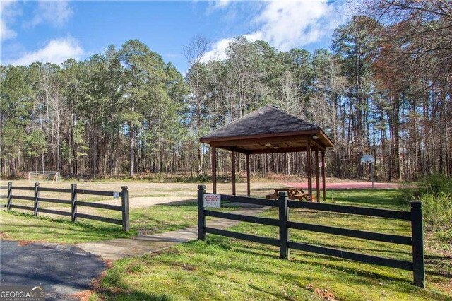 view of home's community with a gazebo, a yard, a view of trees, and fence