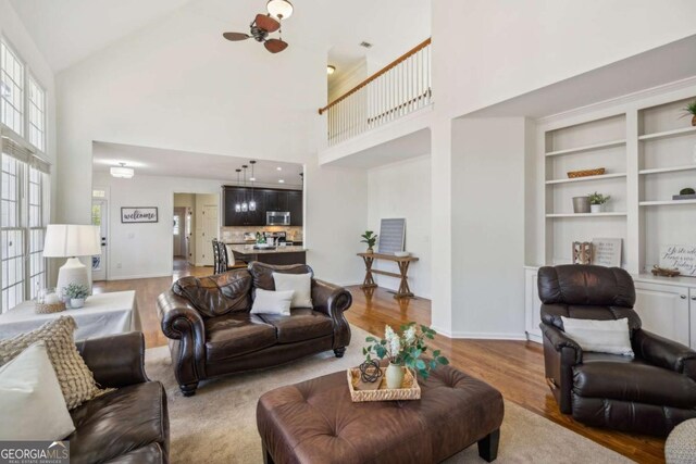 living area featuring wood finished floors, baseboards, and high vaulted ceiling