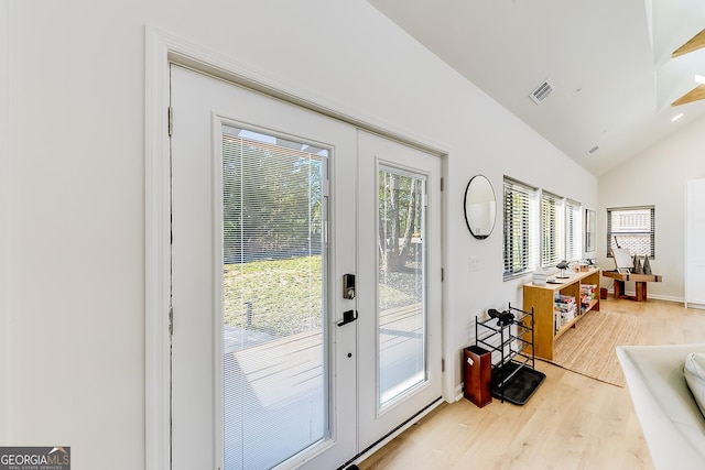 doorway with vaulted ceiling, light wood-style floors, visible vents, and french doors