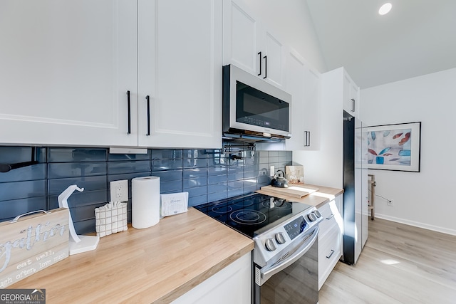 kitchen with tasteful backsplash, white cabinetry, appliances with stainless steel finishes, light wood finished floors, and baseboards