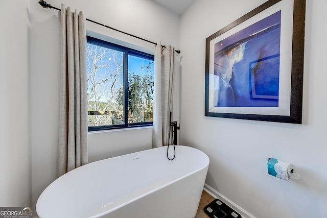 full bathroom featuring a freestanding tub and baseboards