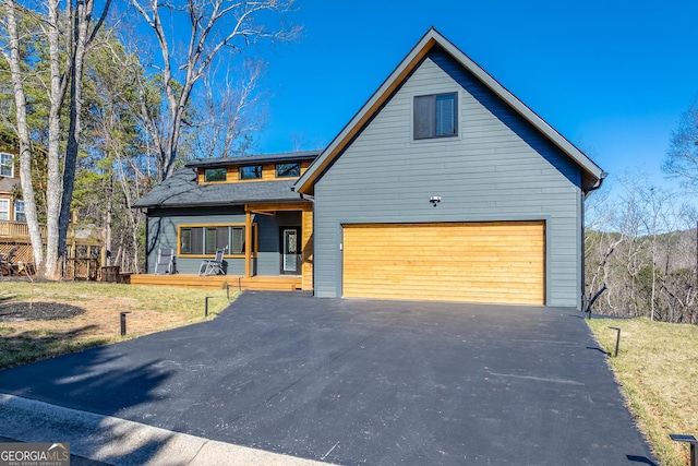 view of front of home featuring aphalt driveway, a front yard, and a garage