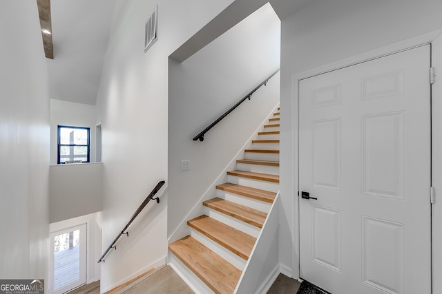 stairway featuring visible vents, a towering ceiling, and wood finished floors