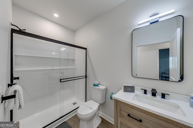 bathroom featuring a stall shower, toilet, vanity, and wood finished floors