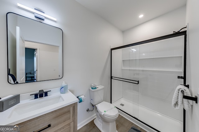 bathroom with vanity, wood finished floors, baseboards, a stall shower, and toilet