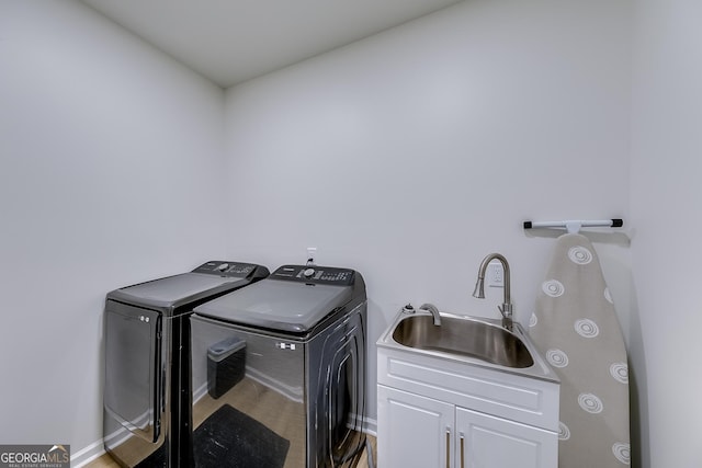 clothes washing area with cabinet space, washing machine and dryer, and a sink