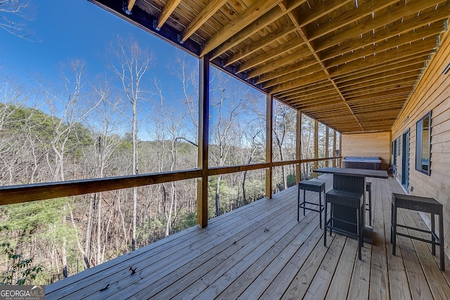 wooden deck featuring a forest view and outdoor dining area