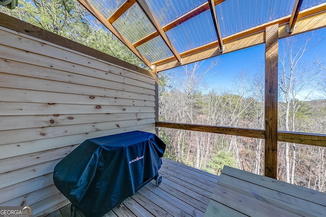 wooden deck with area for grilling and a forest view