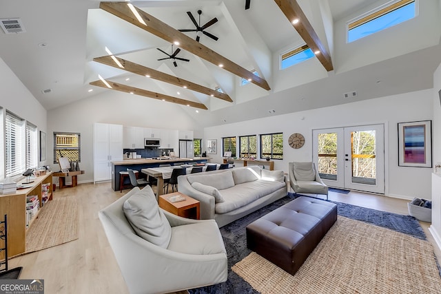 living area with beamed ceiling, light wood-style flooring, visible vents, and a wealth of natural light