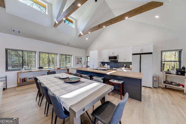 dining room featuring beam ceiling, visible vents, light wood-style flooring, and a healthy amount of sunlight