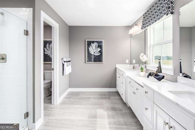 bathroom featuring double vanity, baseboards, and a stall shower