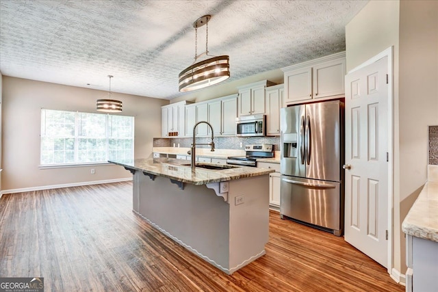 kitchen with dark wood finished floors, tasteful backsplash, appliances with stainless steel finishes, and a breakfast bar