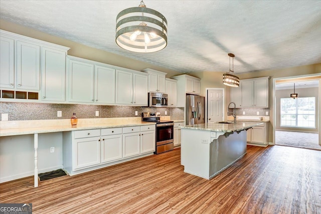 kitchen featuring a kitchen breakfast bar, light wood-style flooring, appliances with stainless steel finishes, and a sink