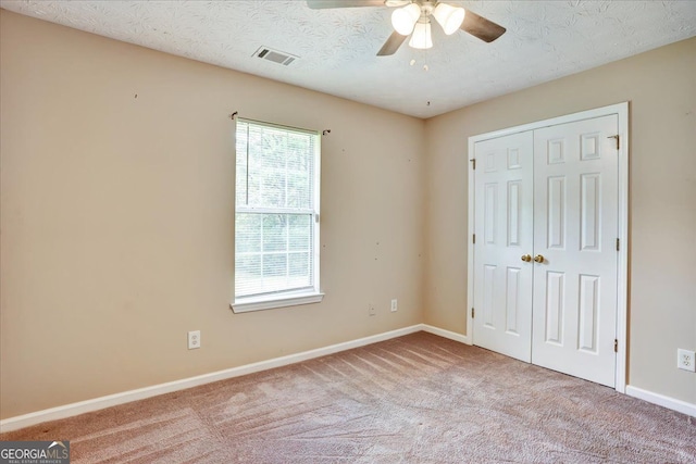 unfurnished bedroom with baseboards, visible vents, carpet floors, a closet, and a textured ceiling