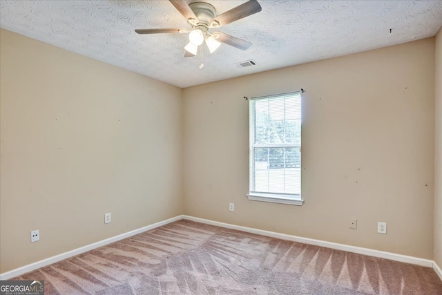 empty room featuring baseboards, visible vents, carpet floors, ceiling fan, and a textured ceiling