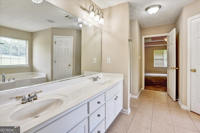 bathroom with a sink, a textured ceiling, double vanity, and tile patterned flooring