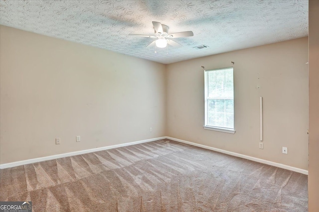 carpeted empty room featuring a textured ceiling, baseboards, visible vents, and ceiling fan