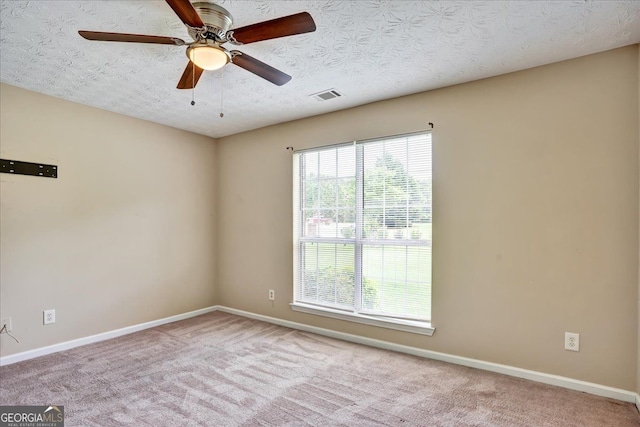 carpeted spare room with visible vents, baseboards, a textured ceiling, and ceiling fan