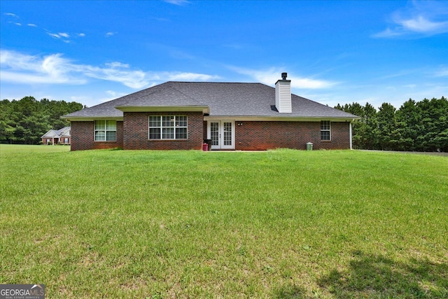 back of property featuring brick siding, a lawn, french doors, and a chimney