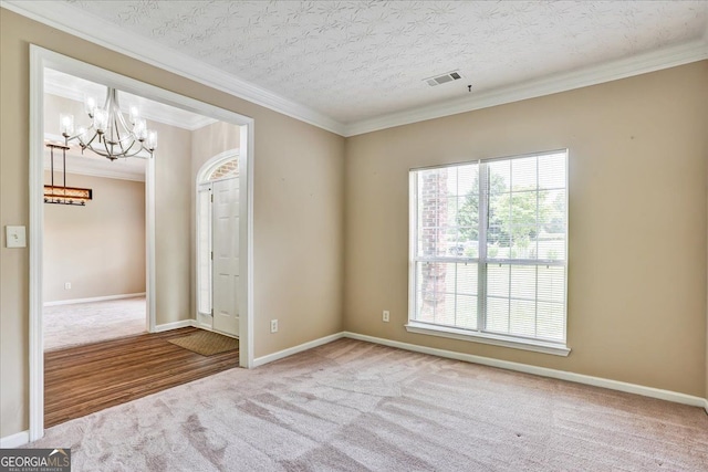 unfurnished room with visible vents, baseboards, an inviting chandelier, crown molding, and carpet flooring