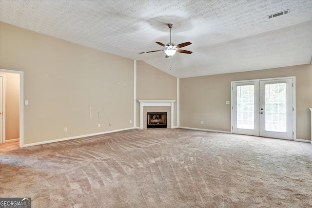 unfurnished living room featuring visible vents, vaulted ceiling, carpet floors, french doors, and a ceiling fan