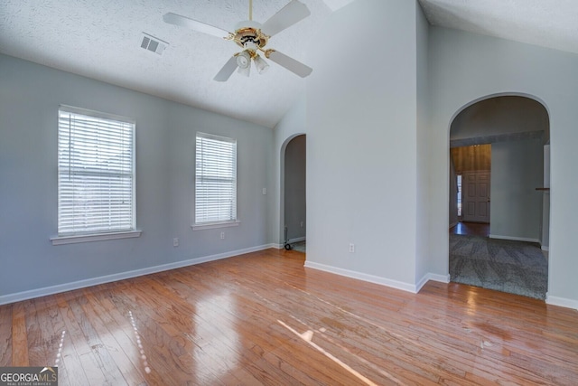 unfurnished room featuring visible vents, a ceiling fan, hardwood / wood-style flooring, arched walkways, and baseboards