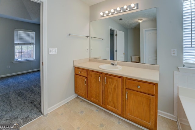 bathroom featuring a bath, visible vents, vanity, and baseboards