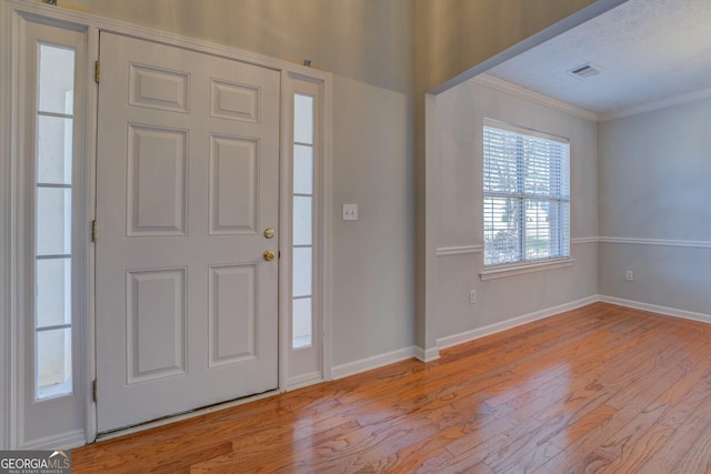 foyer entrance featuring visible vents, baseboards, crown molding, and light wood finished floors