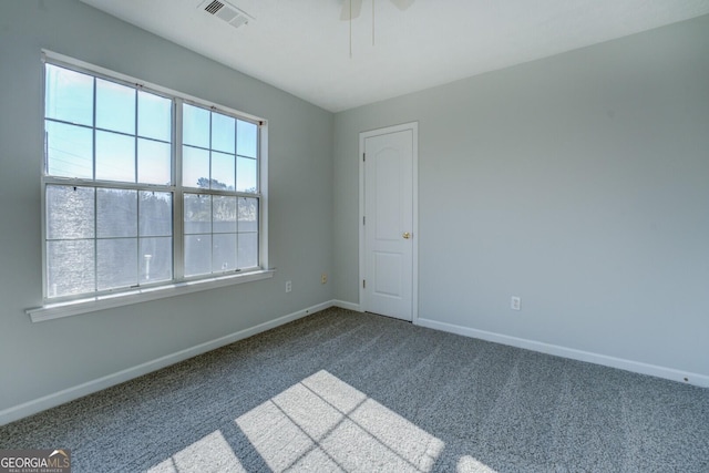 empty room with visible vents, baseboards, ceiling fan, and dark carpet