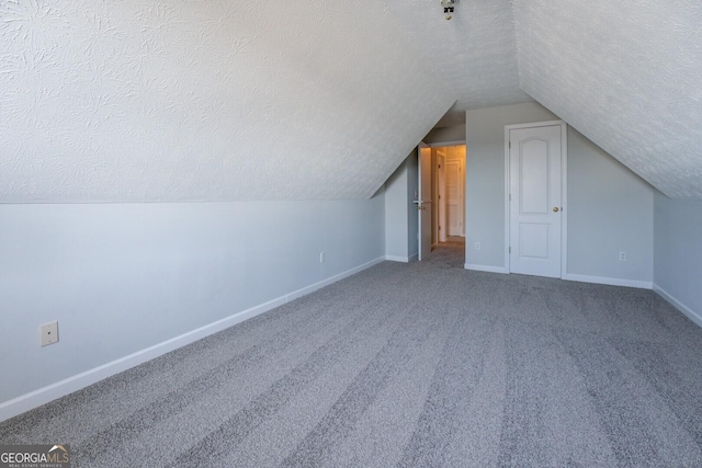 additional living space with baseboards, a textured ceiling, carpet floors, and vaulted ceiling